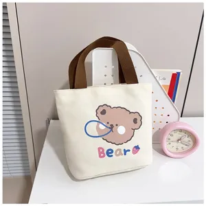 Linda bolsa tote de lona crema con estampado de oso de dibujos animados en un escritorio