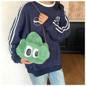 Detalle de un bolso bandolera de peluche verde con diseño de ojos grandes y cadena