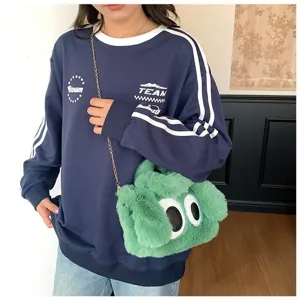 Detalle del bolso bandolera de peluche verde con ojos grandes y correa de cadena