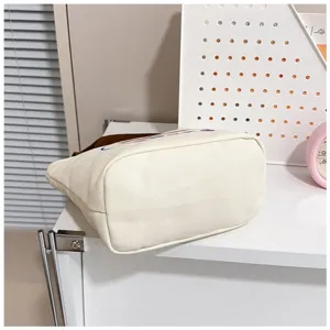 Vista detallada que muestra la base robusta de este bolso tote de lona blanca.