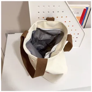 Vista interior del bolso tote grande de lona con forro gris y bolsillo con cremallera