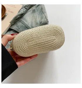 Detalle del fondo ovalado tejido a mano de un moderno bolso de hombro tipo cubo de paja