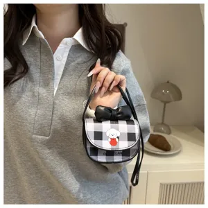 Detalle de un mini bolso bandolera a cuadros con un perro de dibujos y un lazo negro