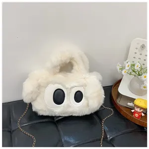 Detalle de un bolso bandolera de felpa blanca con ojos grandes y una cadena dorada.