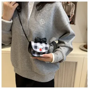 Detalle de mini bolso bandolera a cuadros con estampado de cachorro y lazo