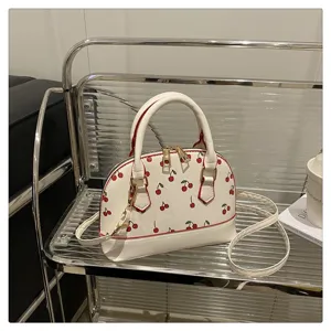 Detailansicht der weißen Muscheltasche mit Kirschmuster und goldenen Details