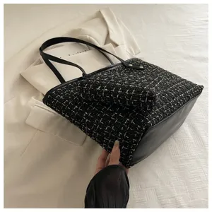Detail van een stijlvolle tweed schoudertas met een bijpassend klein tasje met rits