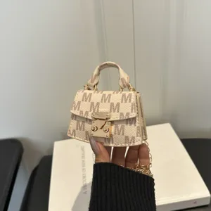 Handheld mini cream luxury accessory bag featuring 'M' monogram and elegant gold chain