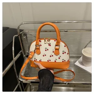 Nahaufnahme der schicken orangefarbenen Muscheltasche mit Kirschmuster und Golddekor
