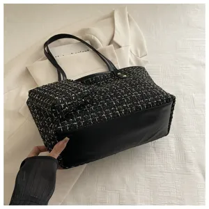 Detail van een zwarte tweed shopper met lederen bodem en bijbehorende kleine tas
