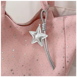 Close-up of a pink star pattern tote bag featuring a silver star charm and cord detail.
