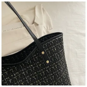 Detailopname van zwart-gouden tweed textuur op een stijlvolle grote dameshandtas
