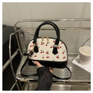 Charmante cremefarbene Muschelhandtasche mit Kirschprint und schwarzen Lederakzenten