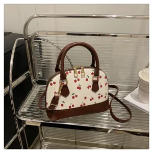 Detailansicht der Muscheltasche mit Kirschprint auf einem modernen Metallregal-Set