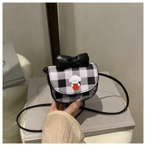 Primer plano de un mini bolso bandolera de cuadros con un lazo negro y estampado de perro.