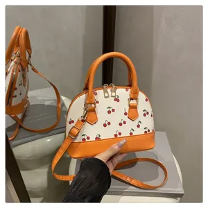 Detailaufnahme einer Kirsch-Print Muscheltasche mit leuchtend orangen Trägern und Akzenten