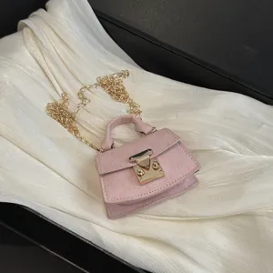 Detailed macro view of a luxury mini pink accessory bag with a gold clasp and chain strap