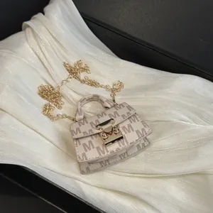 Detail of mini luxury crossbody bag featuring 'M' pattern and elegant gold chain strap