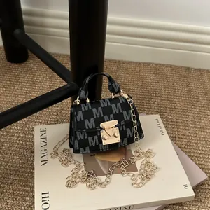 Close-up of a mini luxury crossbody bag featuring M monogram pattern and gold chain strap