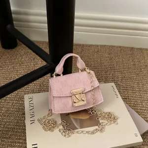 Detailed close-up of a mini pink luxury crossbody bag featuring an elegant gold chain strap