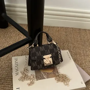 Close-up detail of a mini monogram crossbody bag featuring a gold chain and metal clasp