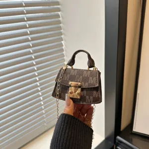 Detail view of a luxury mini brown patterned crossbody bag with gold chain strap