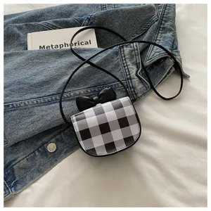 Detalle de mini bolso bandolera a cuadros blancos y negros con un lazo decorativo