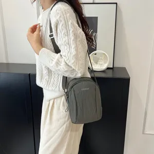Modelo con un mini bolso bandolera informal de nailon impermeable verde oscuro