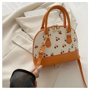 Detaillierte Ansicht des Kirschmusters und des orangefarbenen Riemens dieser Tasche.
