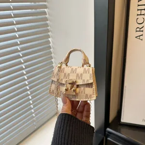 Close-up of a luxury mini monogram crossbody bag with gold-tone hardware detail.
