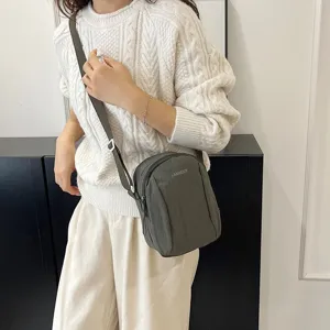 Detalle de un bolso bandolera minimalista de nailon impermeable en una modelo