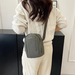Vista trasera de un bolso bandolera minimalista de nailon verde oliva en una modelo