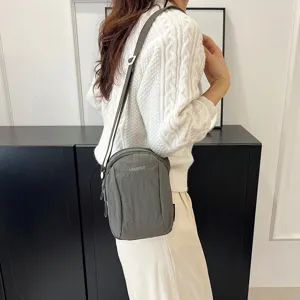 Vista trasera de modelo con un bolso bandolera minimalista de nailon verde oliva.