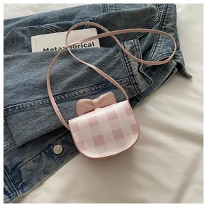 Primer plano de un mini bolso bandolera rosa a cuadros con lazo en chaqueta vaquera