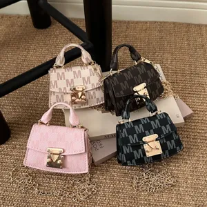 Close-up detail of mini crossbody bags featuring elegant letter patterns and gold chains