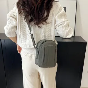 Vista trasera de un bolso bandolera de nailon ligero e impermeable usado por una modelo