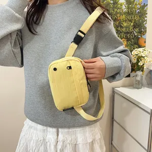 Modelo con un bolso bandolera amarillo de tela Oxford impermeable en un entorno casual
