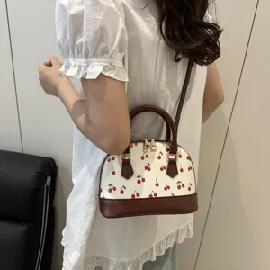 Elegante weiße Muschelhandtasche mit süßem rotem Kirschdruck und braunem Besatz