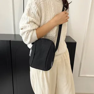 Bolso bandolera informal de nailon negro llevado por una modelo para una foto de detalle
