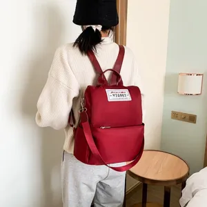Achteraanzicht van een rode waterdichte Oxford-rugzak gedragen door een model in een kamer