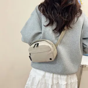 Vista trasera de un bolso bandolera de tela oxford beige combinado con sudadera gris
