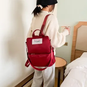 Model met een bordeauxrode waterdichte Oxford-rugzak in een huiselijke omgeving