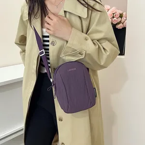 Mujer que lleva un bolso bandolera de nailon morado impermeable y gabardina beige.