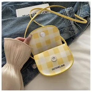 Detalle de cerca de un mini bolso bandolera de cuadros amarillos con cierre de imán.