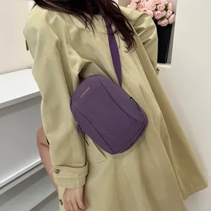 Bolso bandolera de nailon violeta impermeable llevado por una modelo con gabardina beige