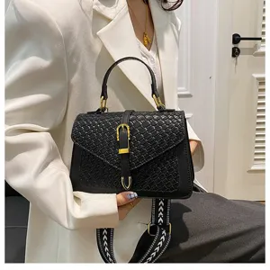 Vista detallada del bolso bandolera negro con textura tejida y elegantes detalles dorados