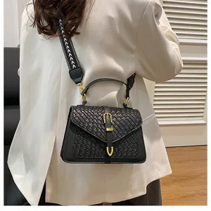 Vista trasera de modelo con un bolso bandolera negro con textura tejida y correa ancha