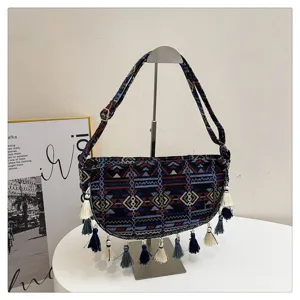 Etnische retro schoudertas met kleurrijke patronen en kwastjes op een displaystand