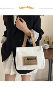 Detail view of a white canvas tote bag with LANSHIYA label held by a stylish model.