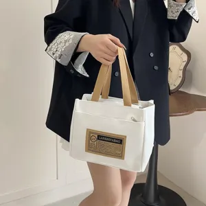 Close-up of Japanese style canvas lunch bag held by a model in casual blazer